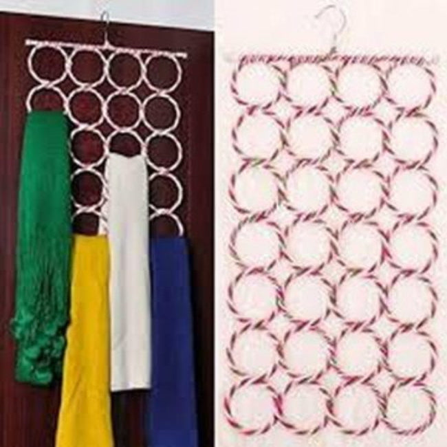 Multicolor 28-hole ring scarf and tie organizer hanging in a closet, fully loaded with various colored scarves, belts, and neckties.
