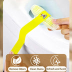 Hand holding a yellow cleaning brush with a brand logo, against a blurred background.