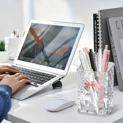 Person using a laptop with a clear pen holder on a desk