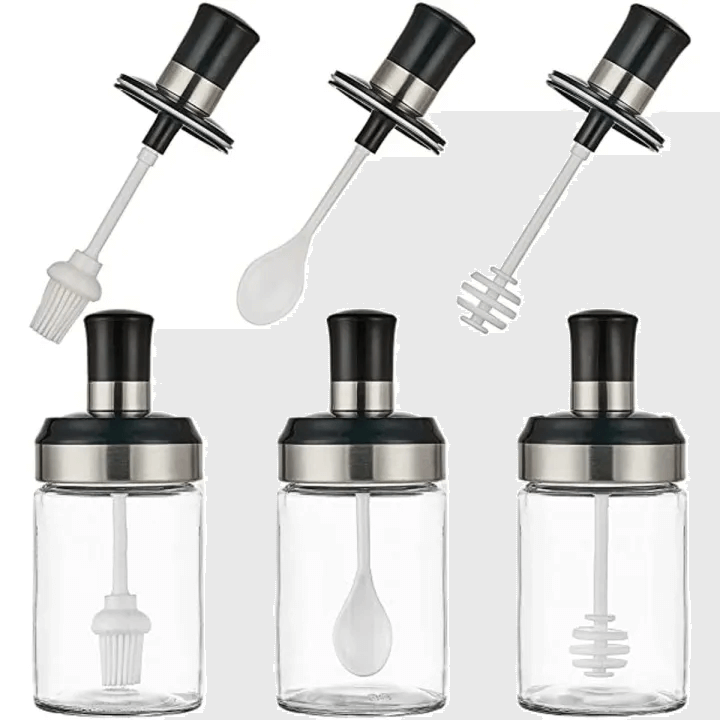 Set of four glass bottles with black and silver lids and attachments on a white background