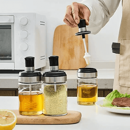 Person pouring a white liquid from a bottle into a glass container on a kitchen counter.