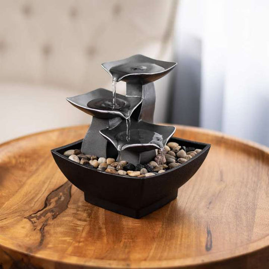 Small water fountain with three-tiered design on a wooden surface