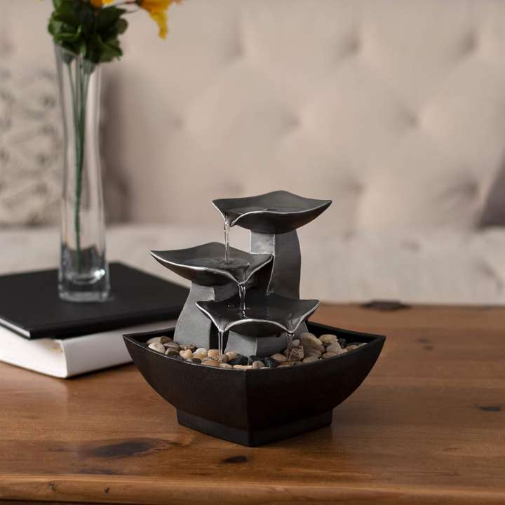 Small indoor fountain on a wooden surface with a blurred background