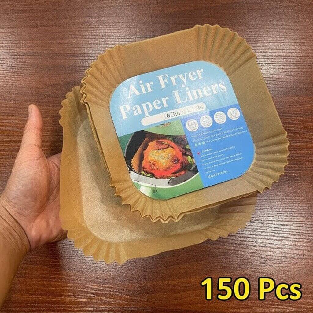 Pack of air fryer paper liners with a hand holding it on a wooden surface.