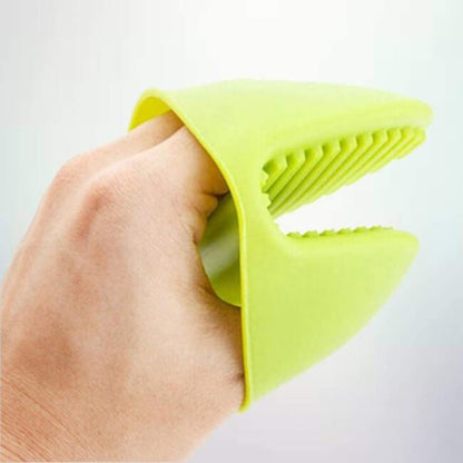 Hand holding a green silicone kitchen tool against a light gray background