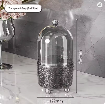 Clear acrylic rotating makeup brush holder organizer with a dustproof lid, full of cosmetic brushes on a vanity desktop