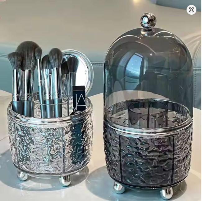 Clear acrylic rotating makeup brush holder organizer with a dustproof lid, full of cosmetic brushes on a vanity desktop