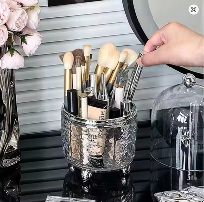 Clear acrylic rotating makeup brush holder organizer with a dustproof lid, full of cosmetic brushes on a vanity desktop