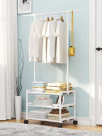 Full view of white adjustable metal clothes rack with 3 wire shelves, holding hanging clothes, shoes, and folded towels in a modern bedroom setting.