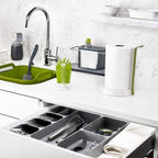 LARGE Grey plastic cutlery tray organizer shown placed inside a kitchen drawer, neatly separating a full set of silver spoons, knives, and forks in the dedicated compartments.