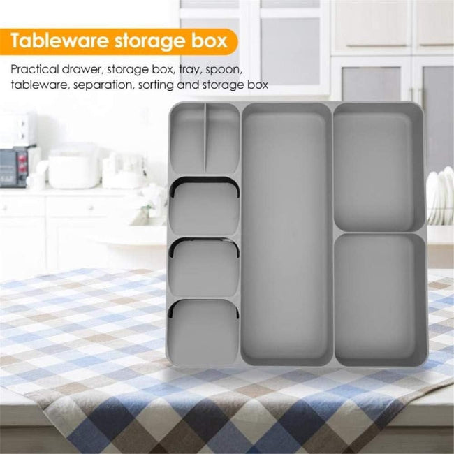 LARGE Grey plastic cutlery tray organizer shown placed inside a kitchen drawer, neatly separating a full set of silver spoons, knives, and forks in the dedicated compartments.