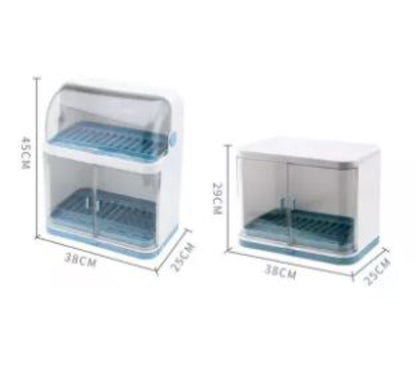 Closed transparent plastic dish drying rack and storage cabinet, shown on a kitchen countertop, neatly holding and covering bowls, plates, and cutlery inside the organized compartments.