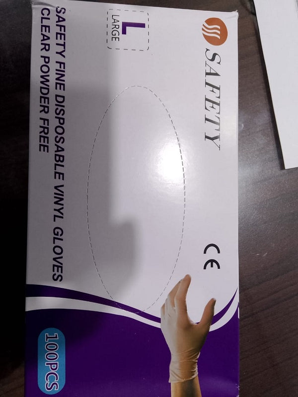 Box of safety disposable vinyl gloves with a hand wearing a glove on a wooden surface