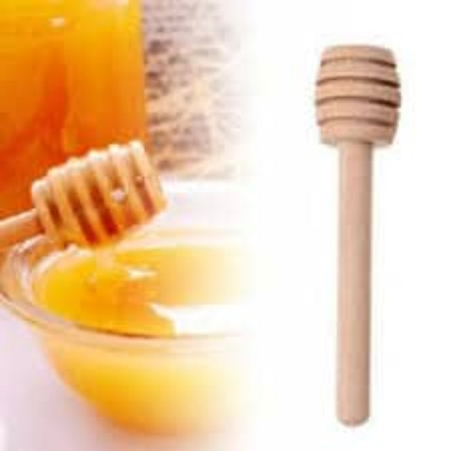 Close-up of a single 8 cm wooden honey dipper stick with a spiral grooved head, shown drizzling golden honey over a slice of toast.