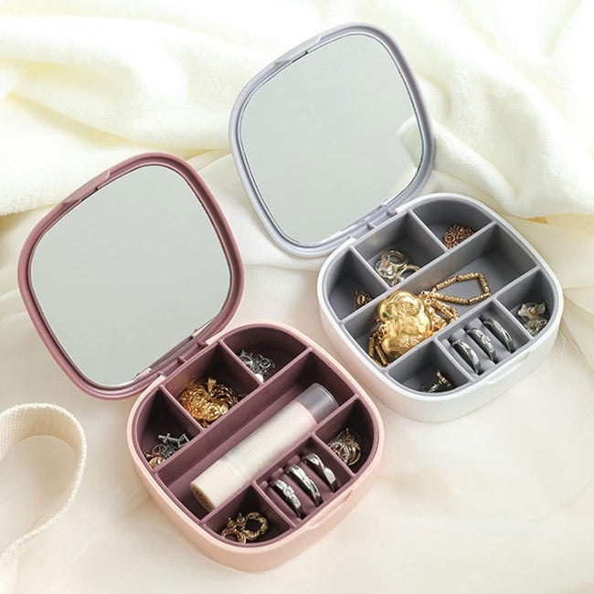 Closed view of a portable jewelry organizer travel box in blush pink, with the lid open showing velvet interior compartments and a built-in mirror.