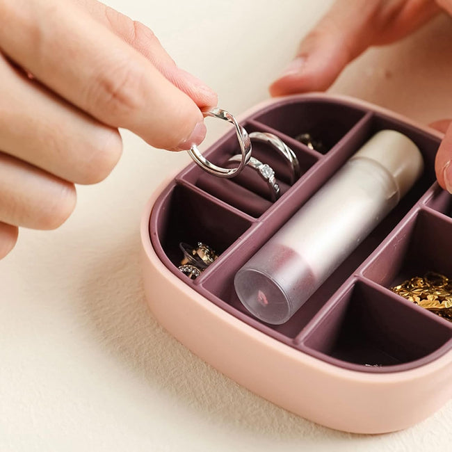 Closed view of a portable jewelry organizer travel box in blush pink, with the lid open showing velvet interior compartments and a built-in mirror.