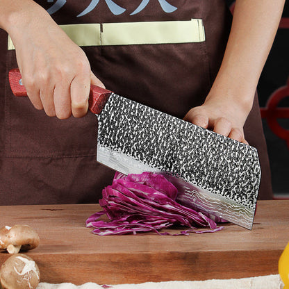 Person using a cleaver to cut purple cabbage on a wooden cutting board.