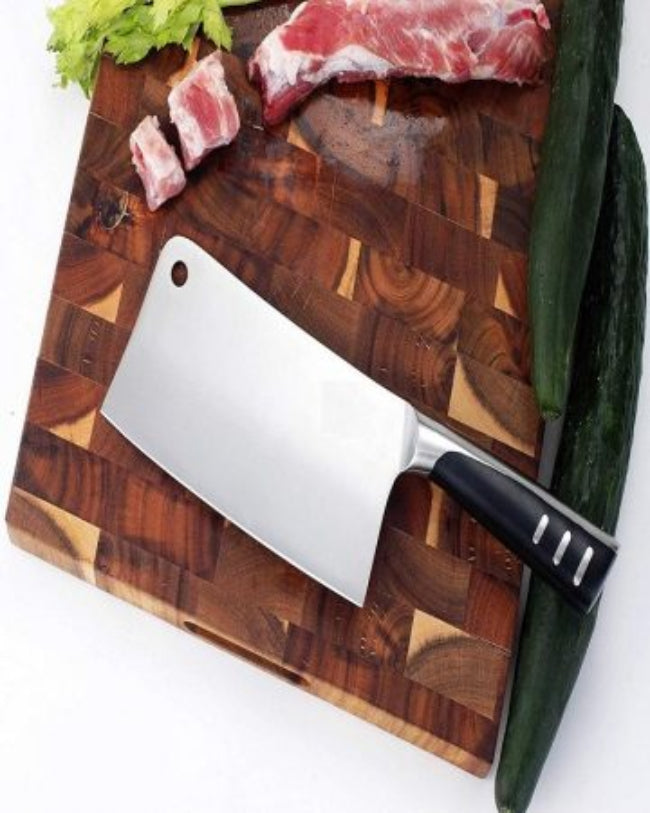 Close-up of a 7-inch stainless steel chopper cleaver butcher knife with a wooden handle, resting on a wooden cutting board next to raw chicken cuts.