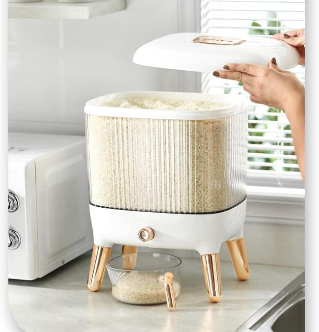 Large 12KG airtight plastic rice and grain storage box with a white lid and transparent body, shown sitting on a kitchen counter next to a scoop, filled with white rice.