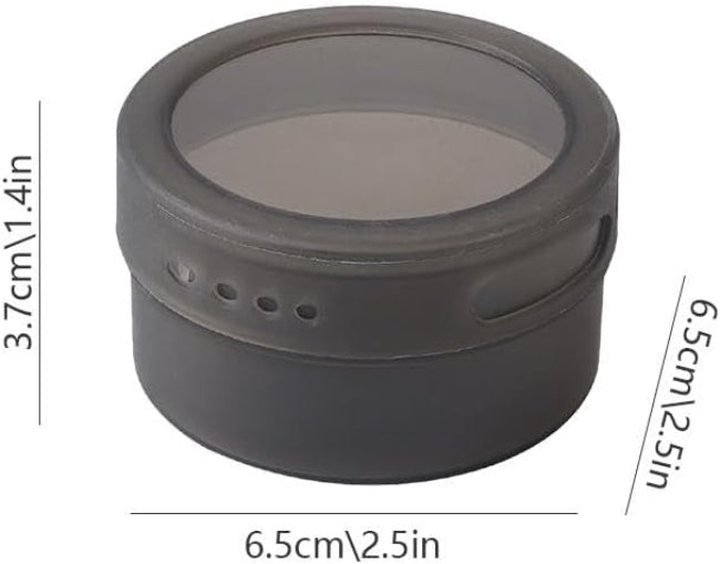 Set of three silver magnetic spice tins with clear transparent lids, shown attached vertically to the side of a stainless steel refrigerator, filled with different colored spices.