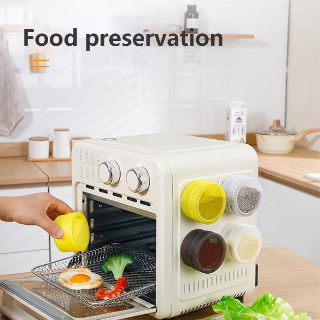 Set of three silver magnetic spice tins with clear transparent lids, shown attached vertically to the side of a stainless steel refrigerator, filled with different colored spices.