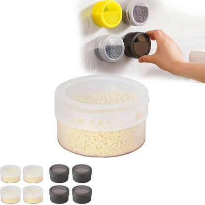 Set of three silver magnetic spice tins with clear transparent lids, shown attached vertically to the side of a stainless steel refrigerator, filled with different colored spices.