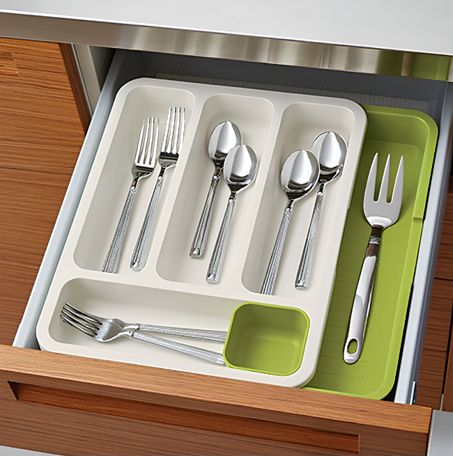 Expandable 2-tier plastic cutlery tray organizer shown fully extended in a kitchen drawer, neatly separating spoons, knives, and forks in the multiple layered compartments.