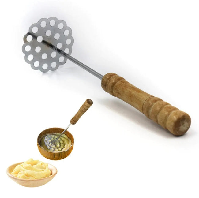 Wooden handle potato masher with a smooth stainless steel mashing plate, shown crushing a bowl of boiled potatoes to create smooth mashed potatoes.