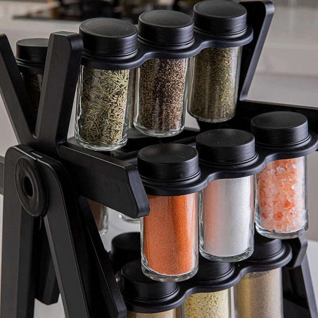 Close-up of an 18-jar stainless steel rotating spice rack organizer designed like a Ferris Wheel, showing the small glass jars filled with various colorful spices and herbs on a kitchen counter.