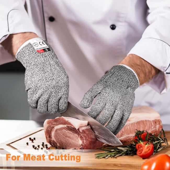 Close-up of a hand wearing a grey Level 5 cut resistant safety glove, securely holding a large onion while the other hand uses a sharp chef's knife for slicing on a cutting board.