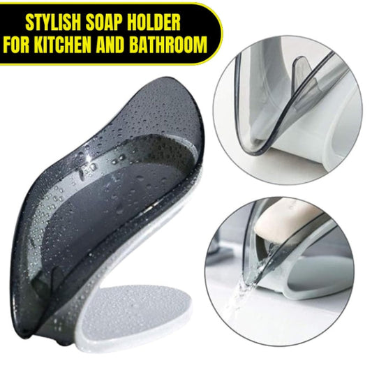 A green leaf-shaped self-draining soap dish holder with a suction cup base, shown on a sink edge, channeling water away from the soap bar.