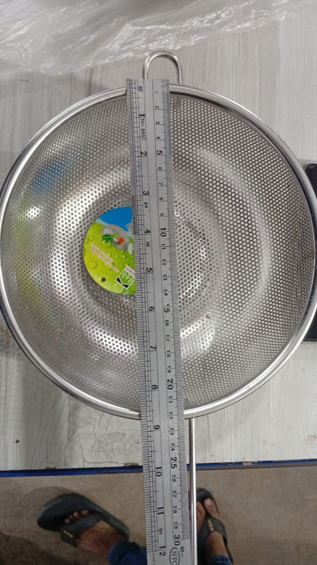 Metal sieve with a ruler for measurement on a light gray background