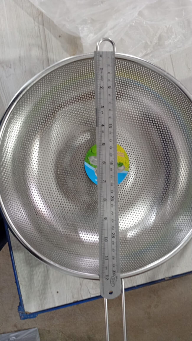 Metal sieve with a ruler for measurement on a light-colored surface
