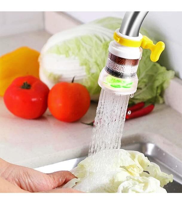 Kitchen faucet attachment with water flowing, vegetables in the background
